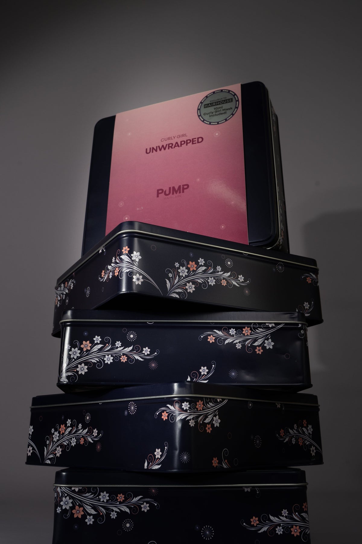 Stack of Pump Unwrapped Christmas Tins in navy with a Curly Girl tin on top